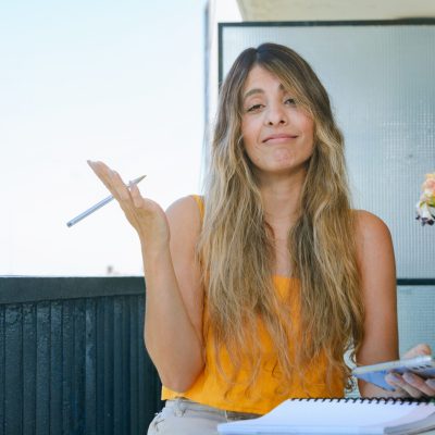 young entrepreneur woman sitting on the balcony looking at the camera making resignation gesture with her hands and face